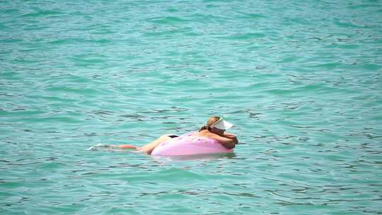 暑假女人漂浮在充气甜甜圈床垫上水玩具游泳