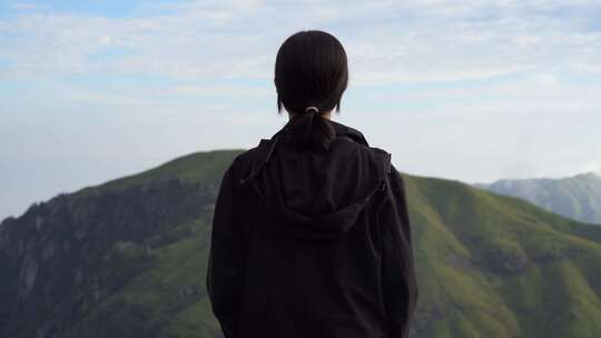 女性青年站在山顶看风景背影看远山感受自然