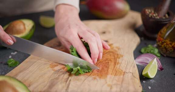 女人在家庭厨房的木制砧板上切割和切碎香菜