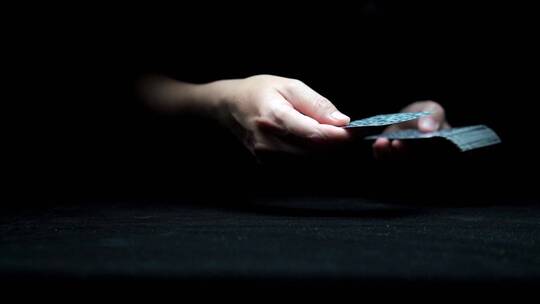 从黑暗中伸出一双玩纸牌的手视频素材模板下载