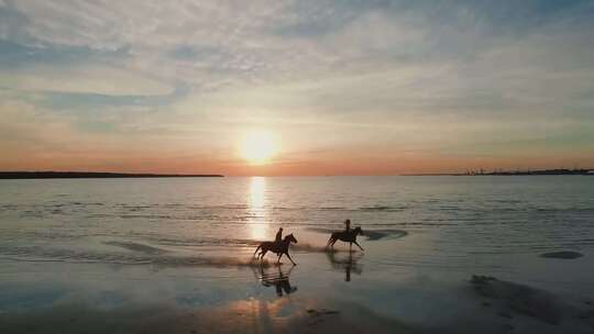 航拍夕阳下海滩上骑马的情侣