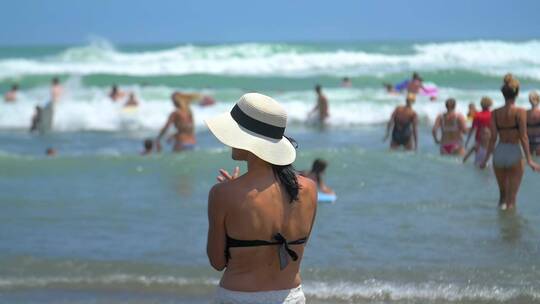 戴帽子的女人站在海滩上