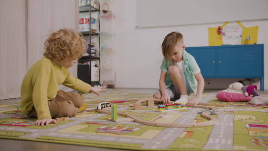两个小男孩在地毯上玩木制汽车