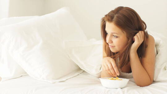 女孩趴在床上吃玉米