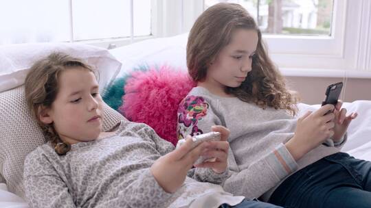 两女孩躺在沙发上玩手机