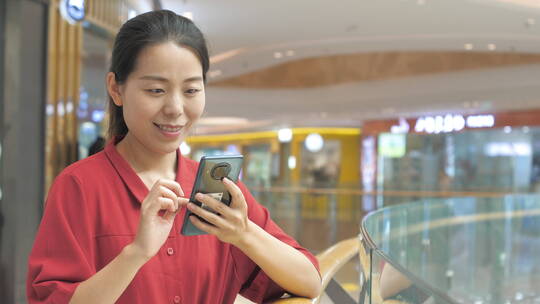 亚洲东方中国女性在商场玩手机沟通联系