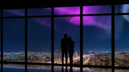 夫妻在大窗户前俯瞰城市