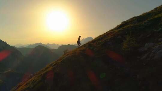 4K-夕阳下攀登山峰的年轻女孩视频素材模板下载