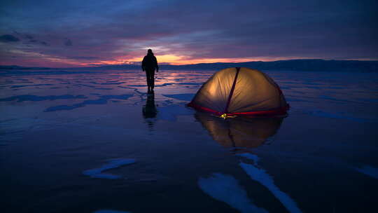 徒步旅行者站在冰冻湖暮光之城冰面上的照明