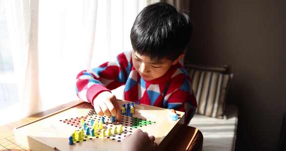 中国小孩在窗边下棋跳跳棋