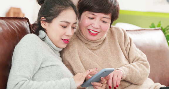 美女和妈妈一起看手机网购母女温馨家庭时光