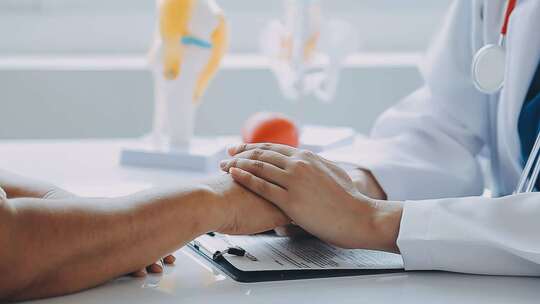 医生与患者双手交握的温馨画面