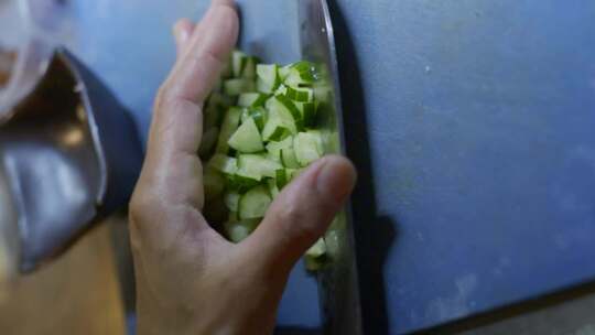 用手和刀把刚切好的黄瓜从砧板上移到沙拉碗