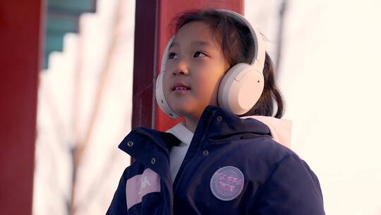 4K冬日坐在公园长廊带耳机欣赏音乐的女孩