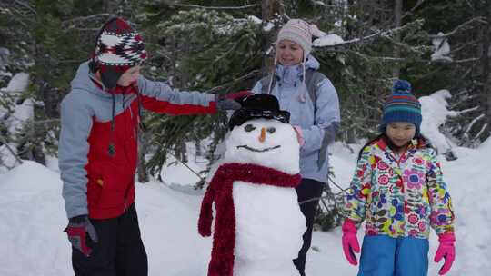 孩子们和他们的妈妈一起堆雪人