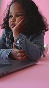 一个正在托腮思考的黑卷发小女孩