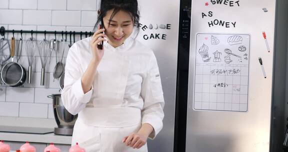 年轻女性烘培师在厨房使用手机通话