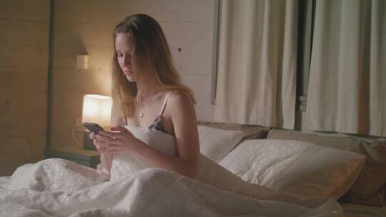 女孩坐在床上玩手机