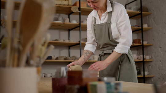 围裙上的女工匠在一个舒适的陶瓷车间里快乐