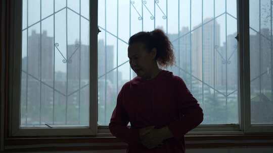 室内窗边中年女性双手抱腹