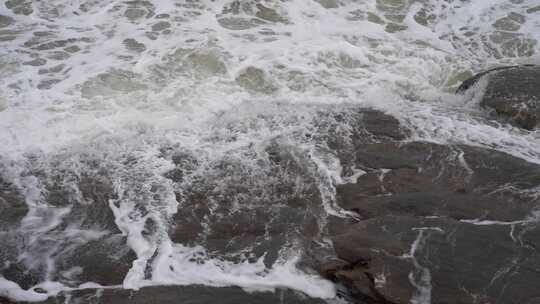 海浪拍打岩石浑浊海水冲刷礁石浪花阴天大海