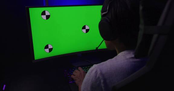 电脑绿色屏幕前的男游戏玩家 