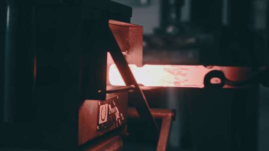工人从铁匠机器中取出一根热金属棒