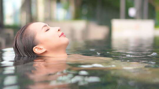 年轻亚洲女子漂浮在豪华度假村或水疗中心的