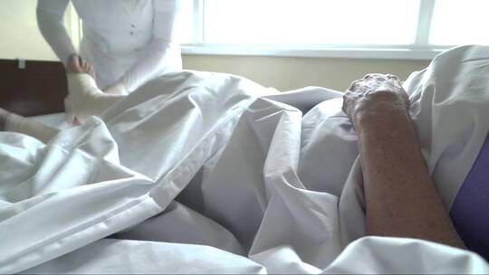 护士手戴防护手套在包扎病人的腿