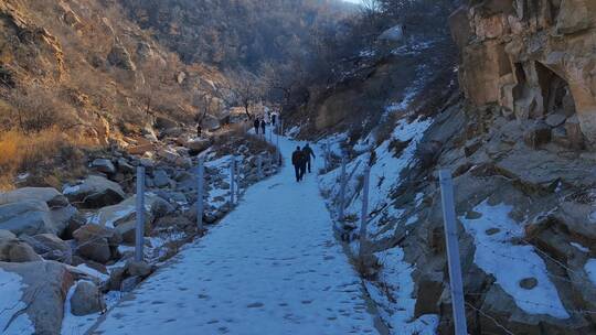 一行人行走在山间雪路上