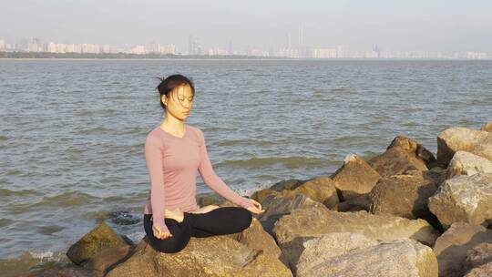 深圳海边岩石上瑜伽打坐的都市女性
