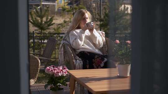 美丽的高加索女人在露台上用鲜花喝茶