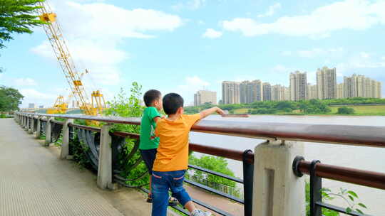 两个小孩在江边爬栏杆看风景