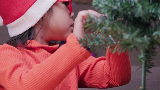 戴圣诞帽的小女孩正在装饰圣诞树视频素材模板下载