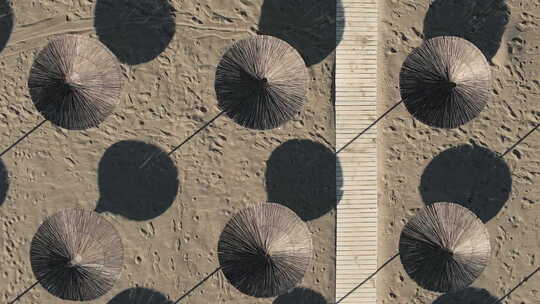 编织的沙滩阳伞和热沙滩上的木板路形成重复的图案视频素材模板下载
