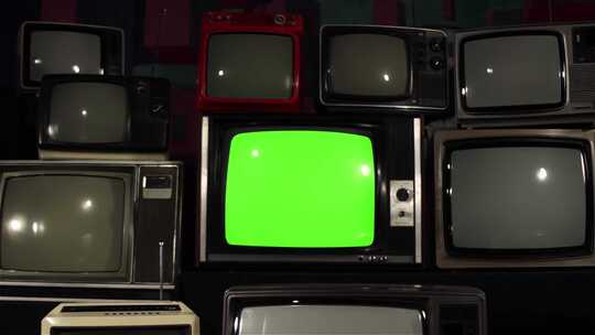 许多复古电视之间带有绿屏的老式电视机。多莉在。4K版。