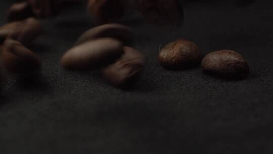 咖啡豆掉落在黑色桌子上旋转的特写镜头。宏