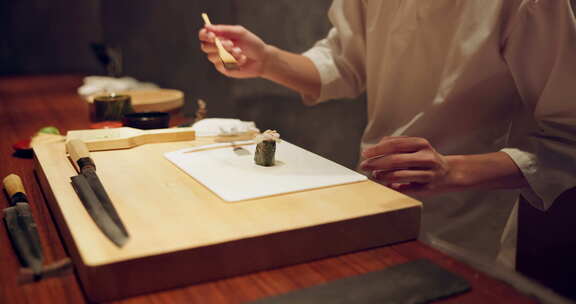 寿司、鱼和厨师双手的特写镜头，晚上在餐厅