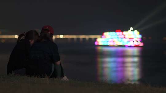 两人坐在江边看长江游船夜景