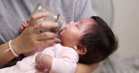 一个新生儿的特写镜头，她正在从奶瓶里吮吸