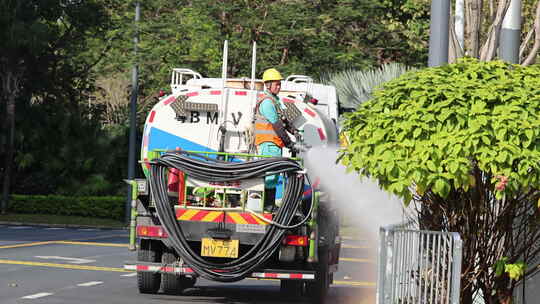 环卫工操作洒水车进行街道喷灌作业