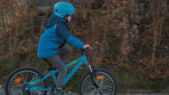 穿蓝夹克的男孩骑着自行车视频素材模板下载