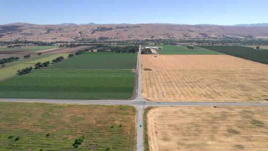 无人机拍摄的浅蓝色经典芥末在加州乡村公路上行驶的镜头