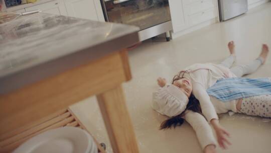 躺在厨房地上玩耍的姐妹