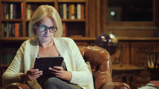 女人坐在图书馆的沙发上使用平板电脑视频素材模板下载