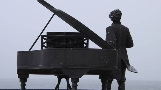 雪花飘落之中的威海幸福公园海上钢琴师雕像