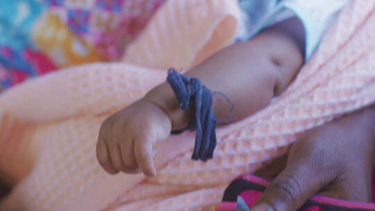 非洲火车上母亲怀里的婴儿小手紧握蓝色布条