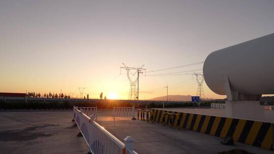 夕阳下高压电线塔附近巨大的储气罐航拍