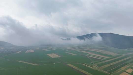 田野山峦雾气蒸腾山顶云雾大风车若隐若现