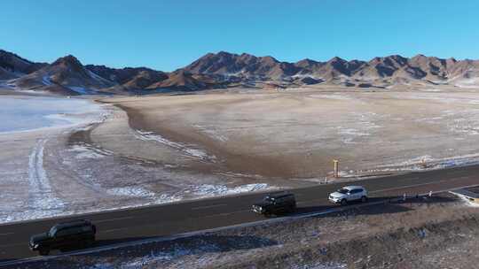 航拍冬季新疆赛里木湖雪山环湖公路夕阳车辆